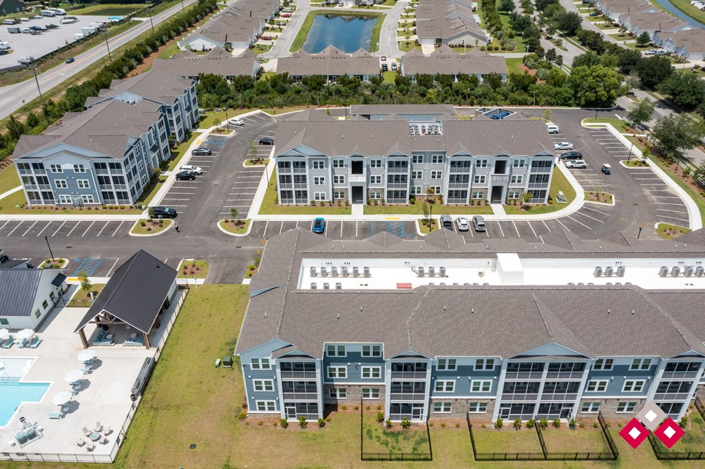 an aerial view of an apartment complex with a parking lot and a swimming pool