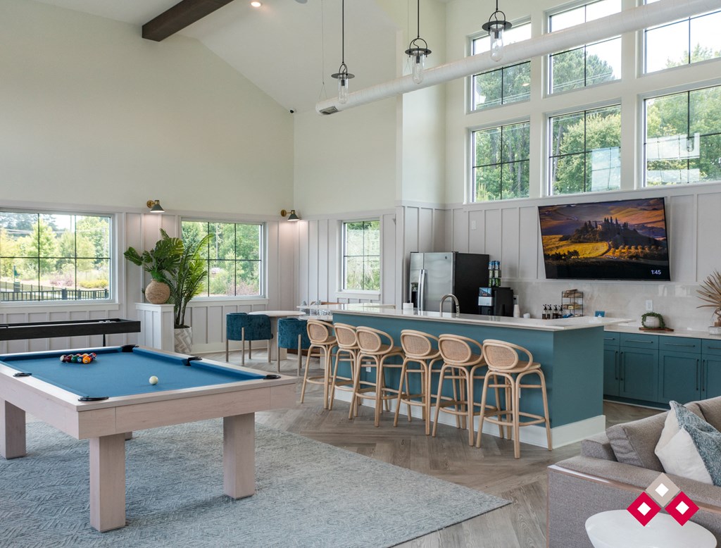 a pool table in the center of a living room with a bar and a kitchen