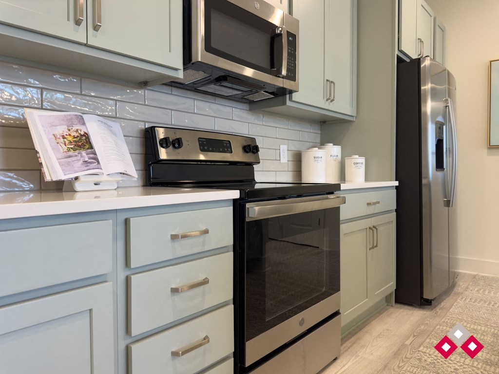a kitchen with white cabinets and stainless steel appliances and a refrigerator