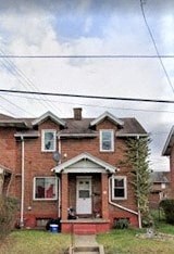 A red brick house with a white door and a small porch.