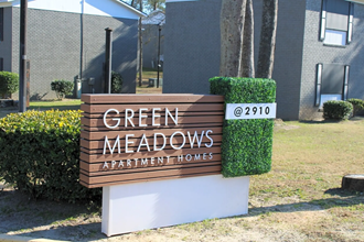 the sign outside of the green meadows apartment homes building