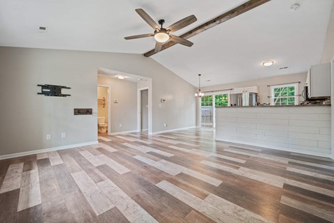 A spacious room with a ceiling fan and wooden flooring.