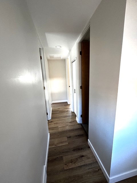 a hallway with wooden floors and white walls and a door