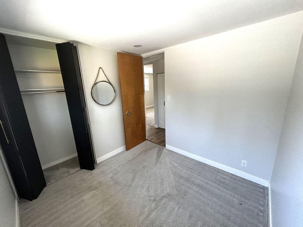 a large empty room with a door to a closet and a mirror