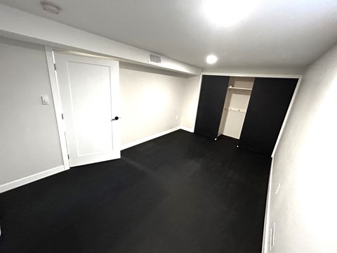 an empty room with black flooring and white walls