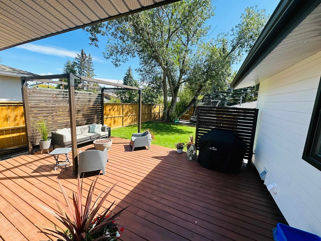 a patio with a grill and a wooden deck