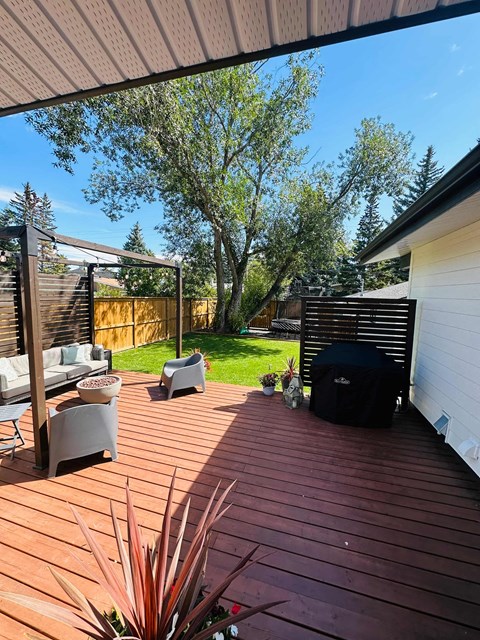 a backyard with a wooden deck and a tree