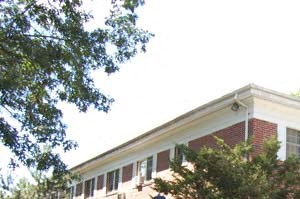 a brick building with trees and bushes in front of it