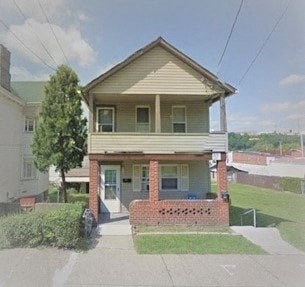 a small house with a porch and a street in front of it
