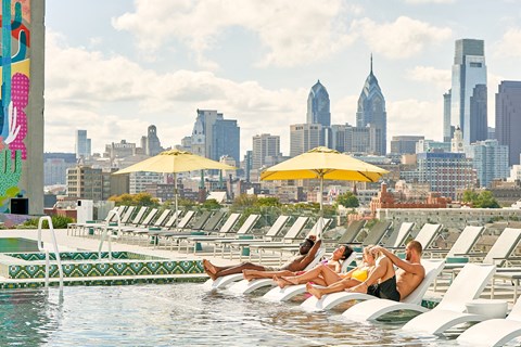 a group of people sitting on rafts in a pool with a city skyline in