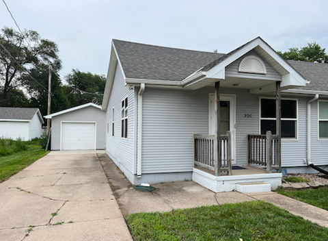 A small house with a porch and a garage door.