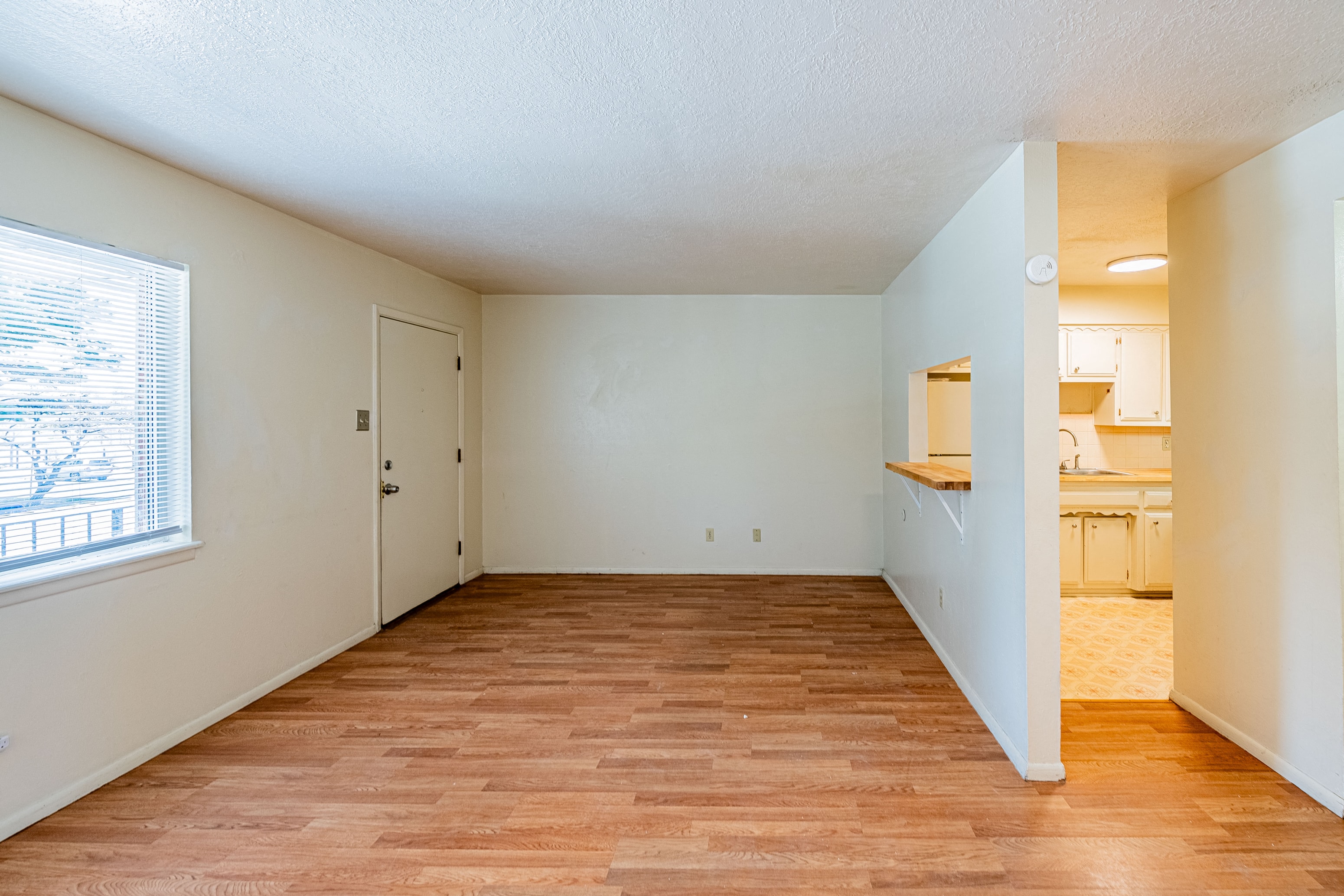 an empty living room and kitchen with a large window