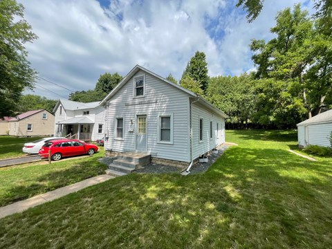 A white house with a red car parked in front.
