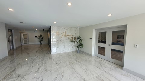 A spacious room with marble flooring and a large mirror on the wall.