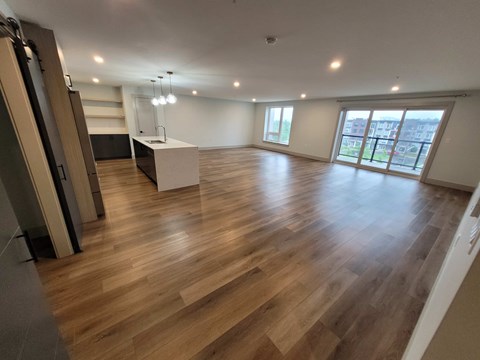 A spacious room with wooden flooring and a large window.