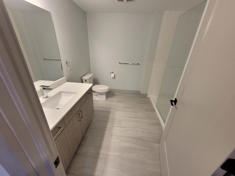 A bathroom with a toilet, sink, and mirror.