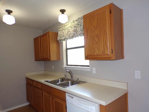 A kitchen with wooden cabinets and a white dishwasher.
