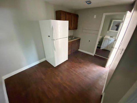 a small kitchen with a refrigerator and a wooden floor