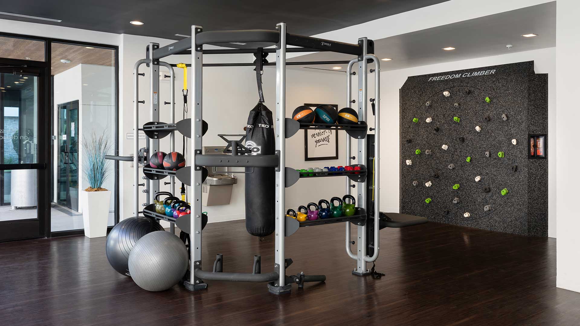 A gym room with a lot of equipment and rock climbing wall.