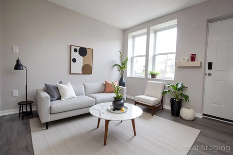 A living room with a grey couch, a coffee table, and a painting on the wall.