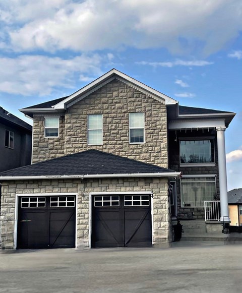 a stone house with two garage doors in front of it