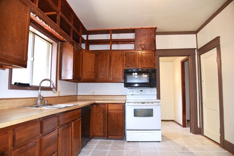 a kitchen with wooden cabinets and a white stove and microwave