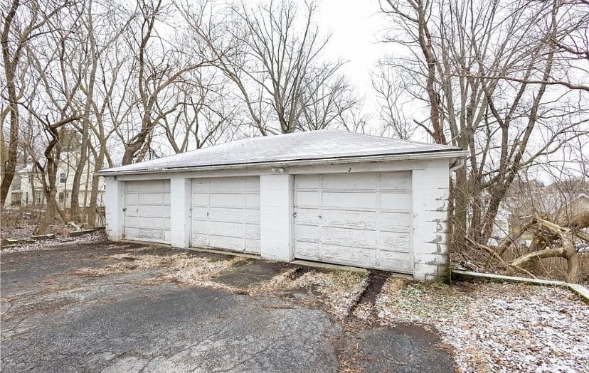 a small garage with white doors on the side of the road