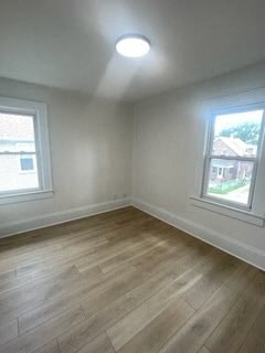 an empty room with wooden floors and two windows