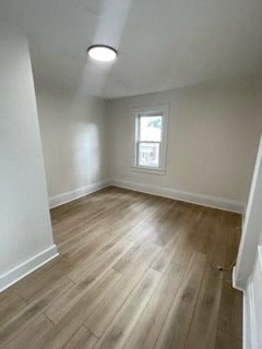 an empty living room with wood floors and a window
