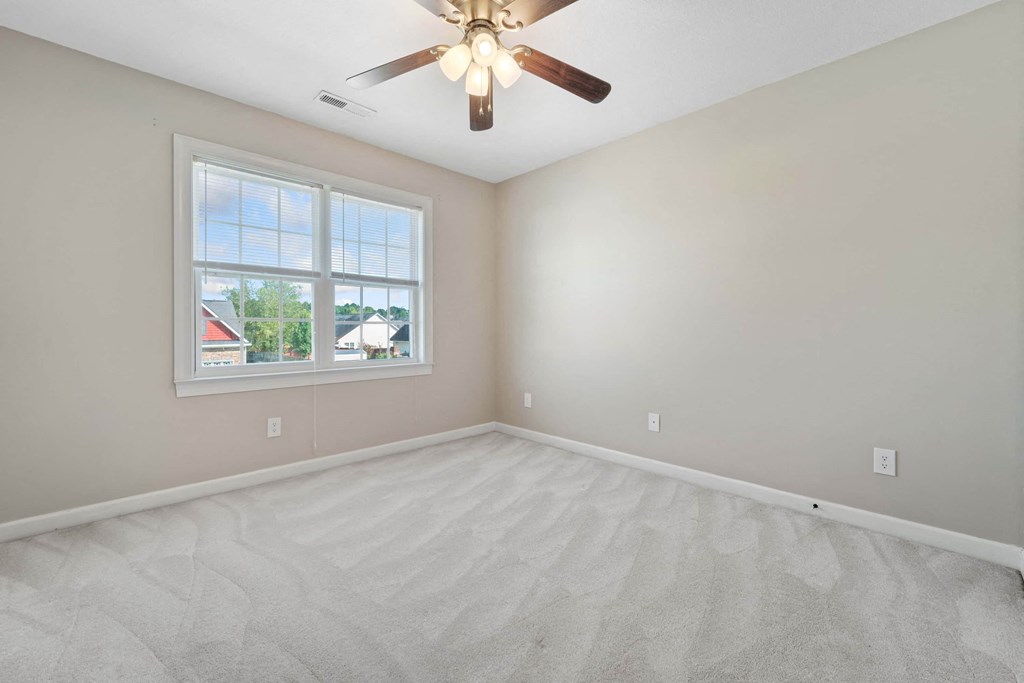 an empty living room with a ceiling fan and a window
