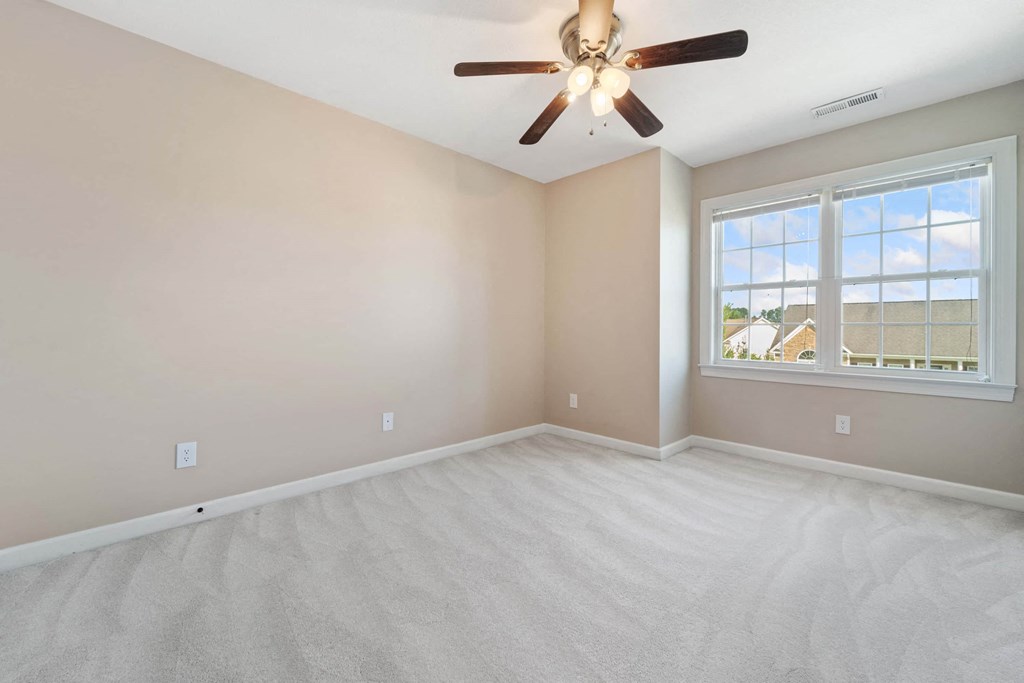an empty living room with a ceiling fan and a window