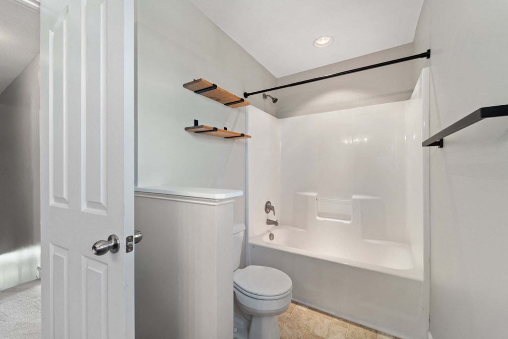 a bathroom with a toilet and a tub and a shower