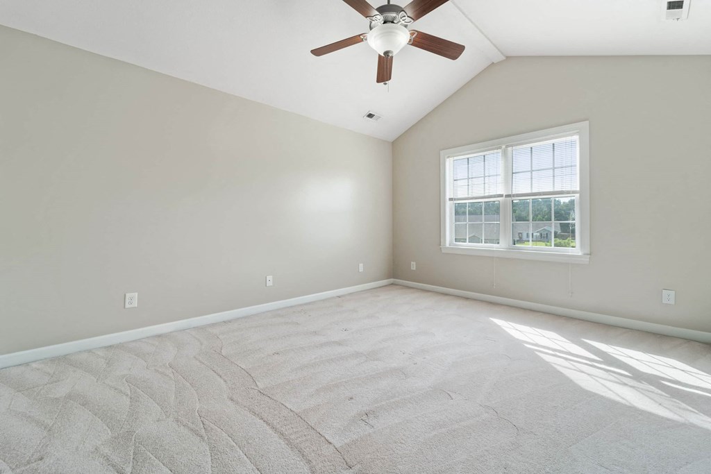 an empty living room with a ceiling fan and a window
