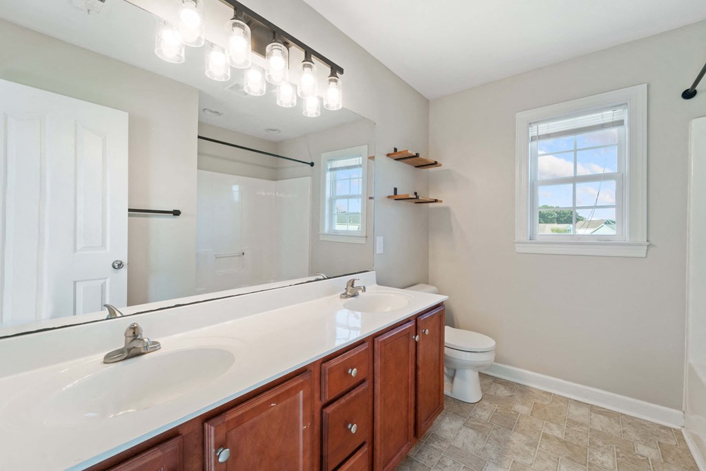 a bathroom with two sinks and a toilet and a mirror
