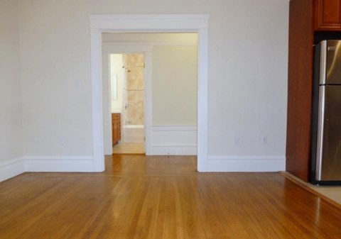 A kitchen with a refrigerator on the right and a doorway leading to another room.