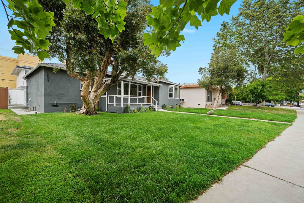 a gray house with a lawn and trees in front of it