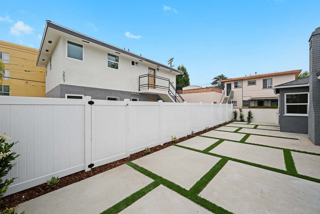 a white fence in front of a yard with houses
