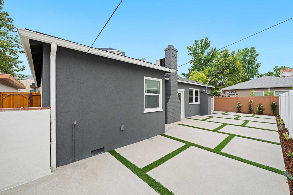 a backyard with a gray house and a yard with grass