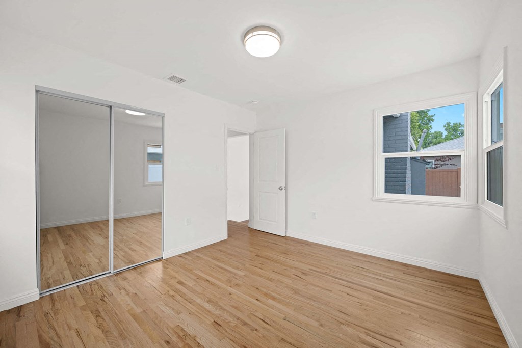 a living room with wood floors and a mirrored closet