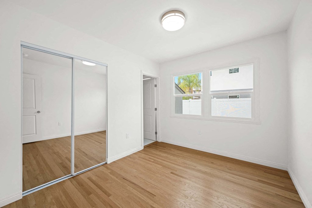 a bedroom with a mirrored closet and a window