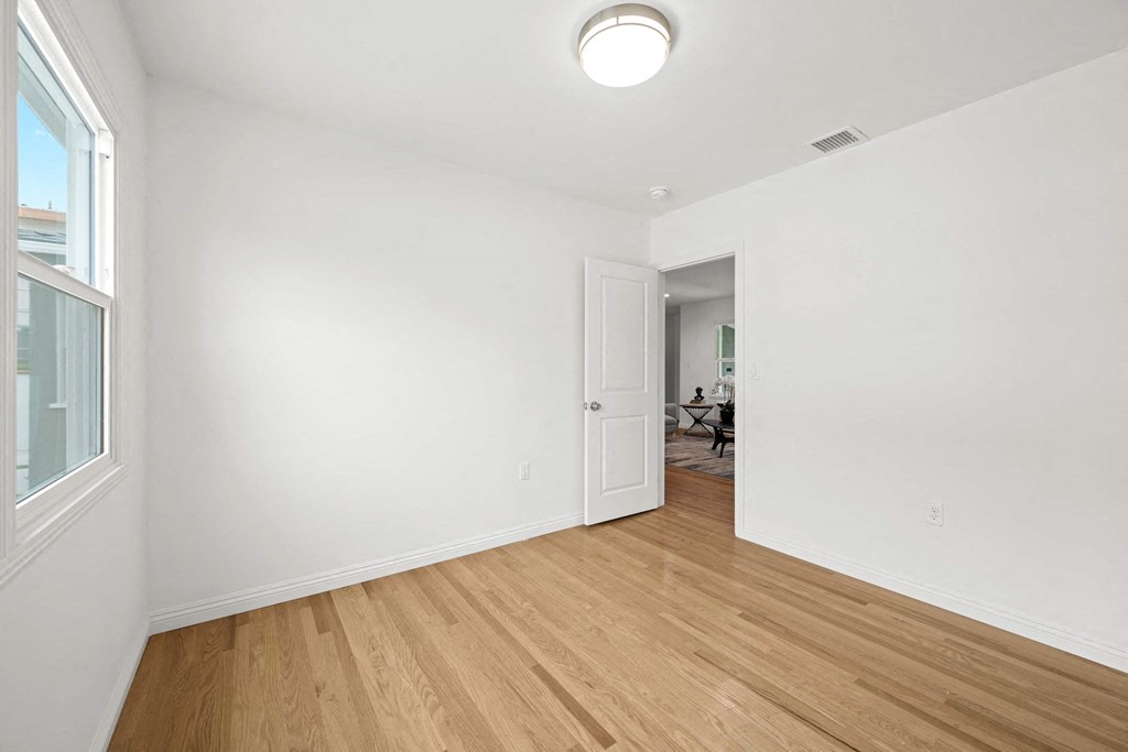 a renovated living room with white walls and wood floors