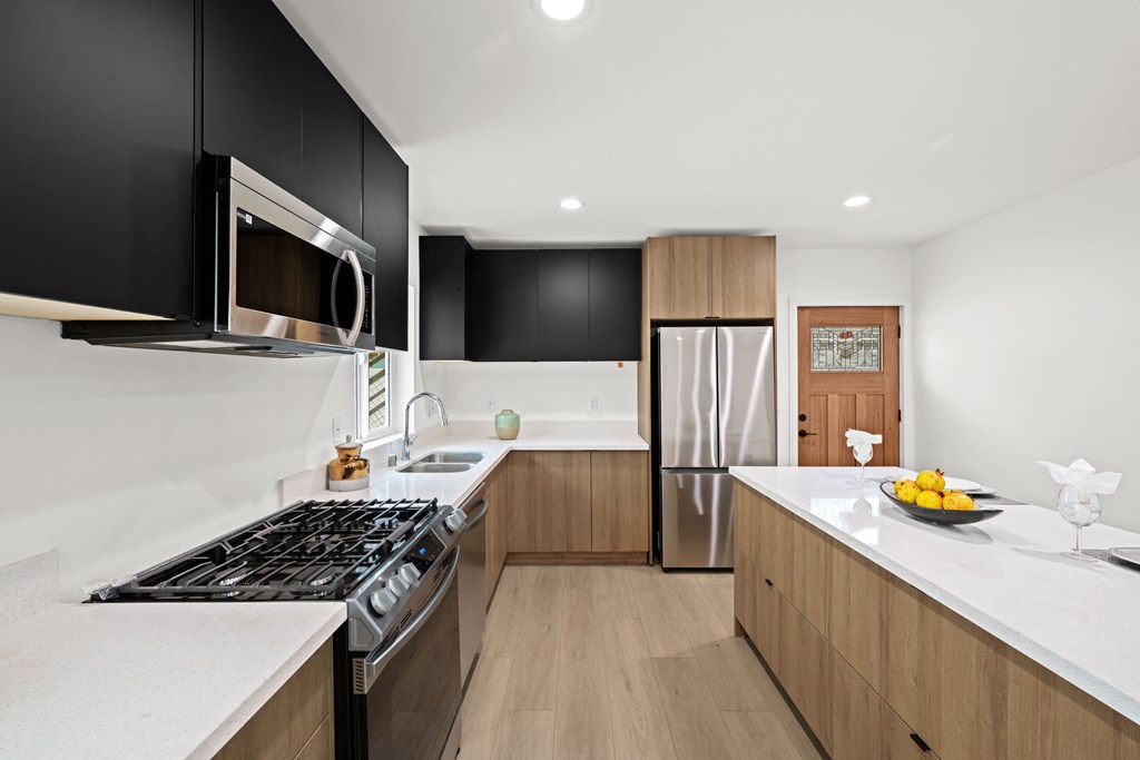 a kitchen with wooden cabinets and white counters and a stainless steel refrigerator