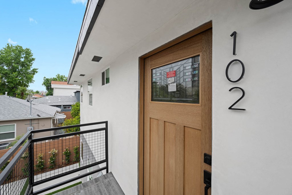 the front door of a white house with a wooden door