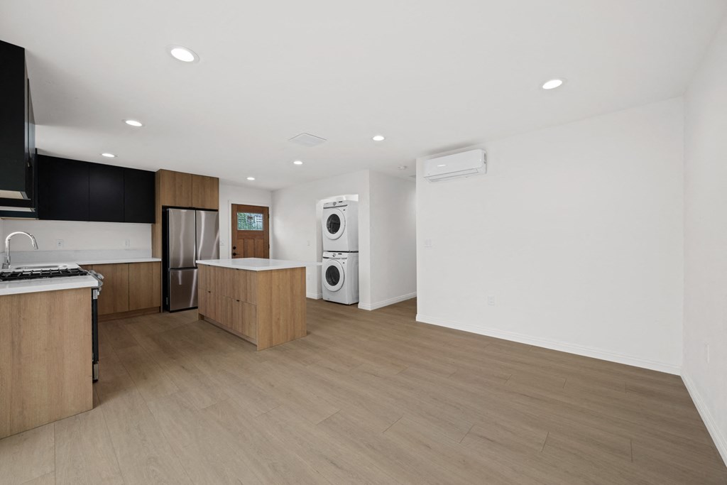 an empty kitchen and laundry room with wood floors and white walls