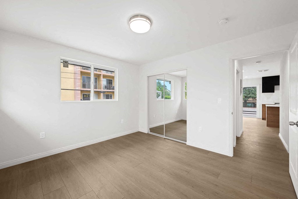 an empty living room with a mirror and a door to a hallway