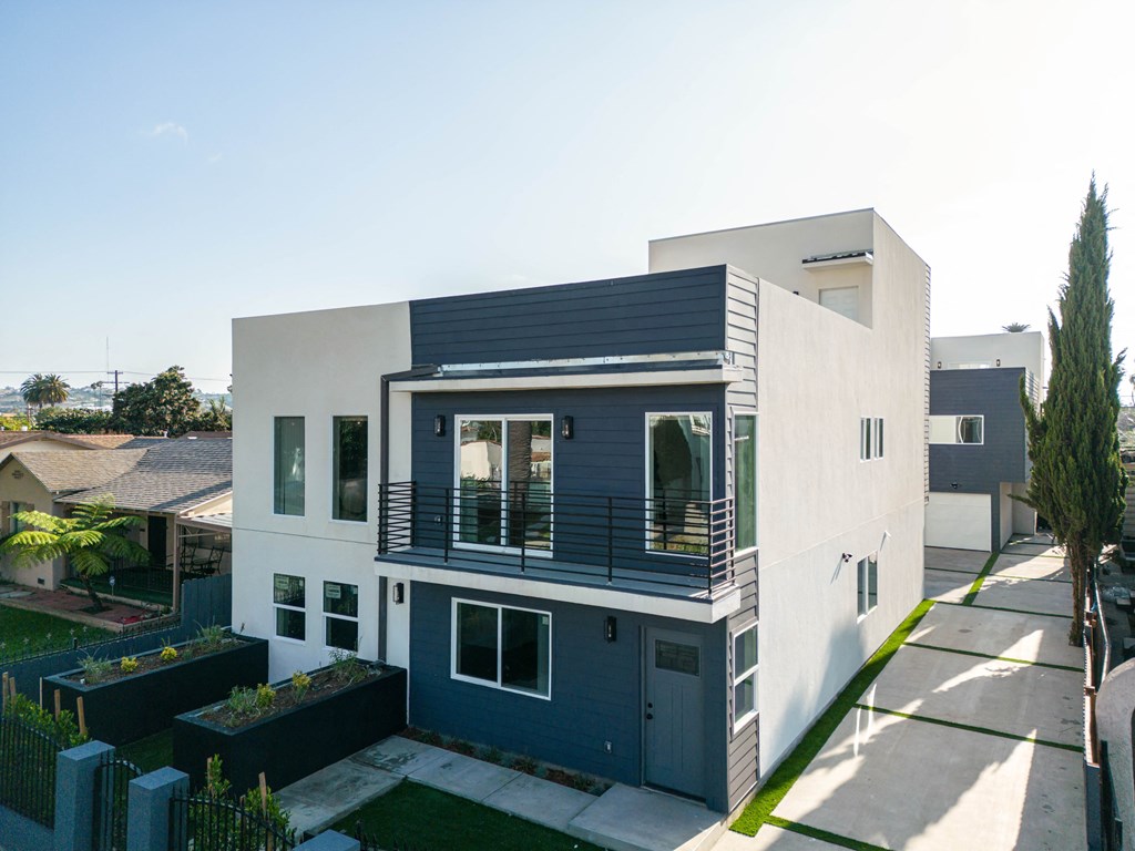 a white and blue house with a balcony and a yard