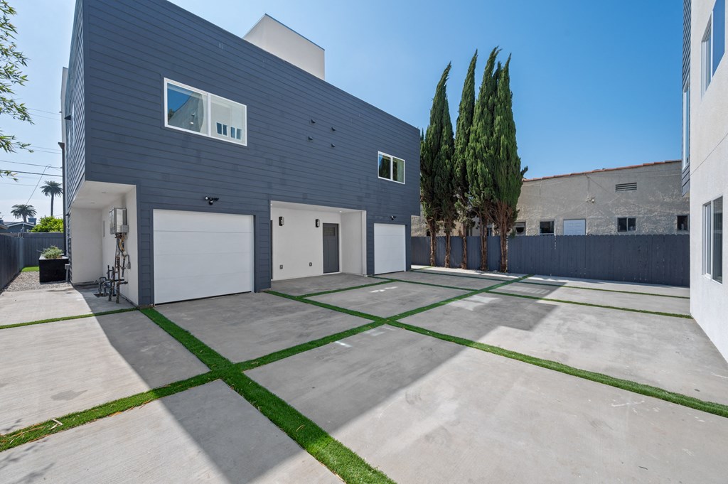 the driveway of a house with two white garage doors and a driveway with grass