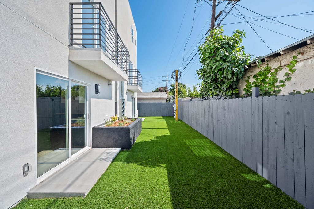 a backyard with green grass and a fence and a glass door