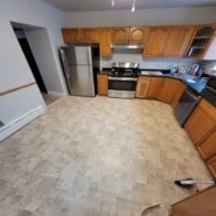 A kitchen with wooden cabinets and a tile floor.