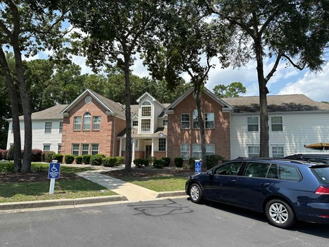 A blue car is parked on the side of a street in front of a brick building.
